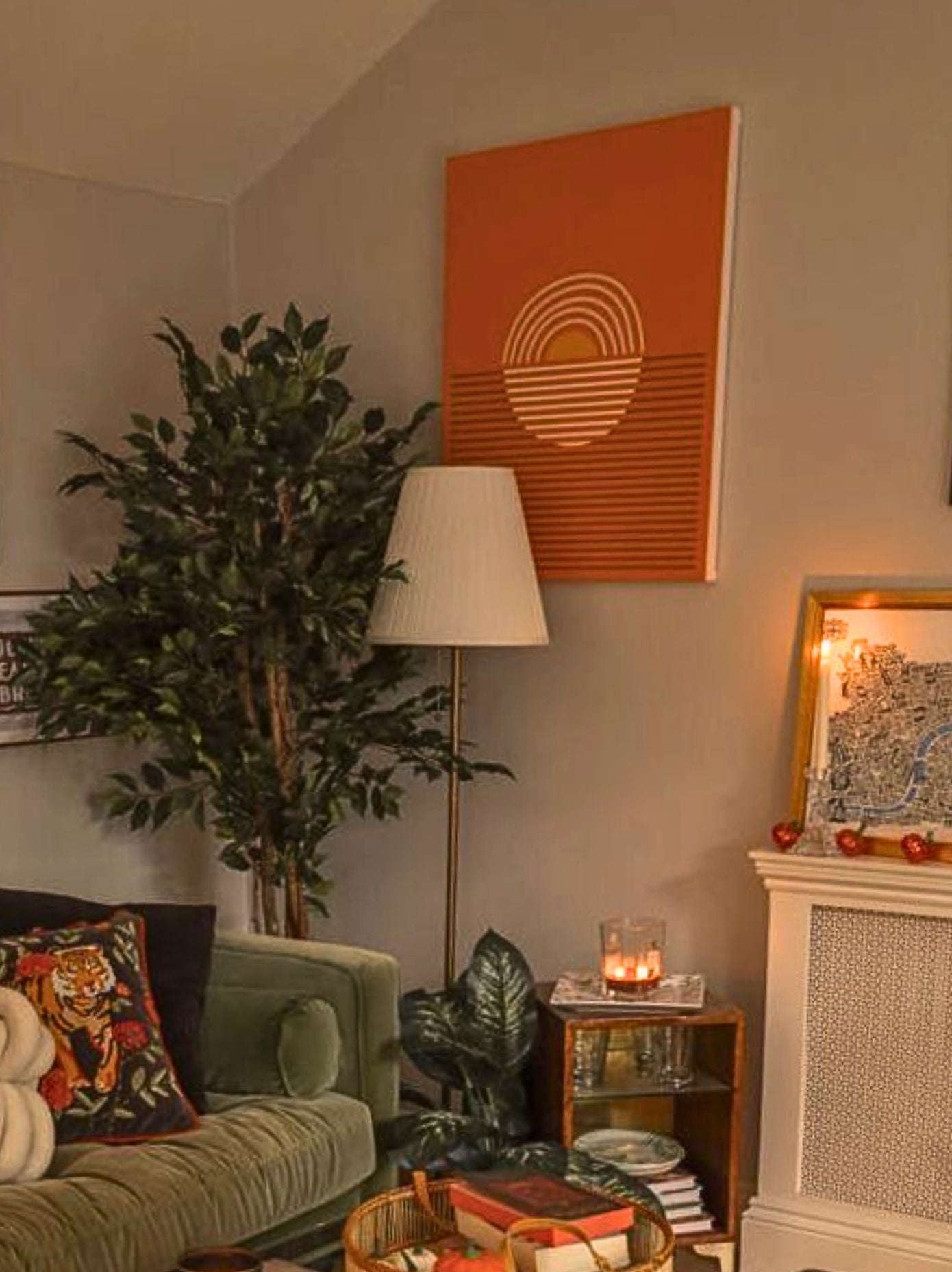 Living room with a green sofa, decorative pillows, a plant, and wall art.