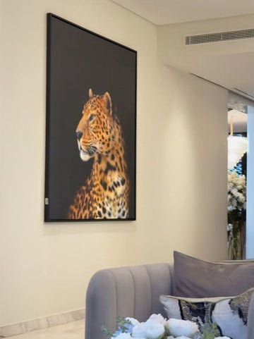 Framed canvas of a leopard on a wall in a room with a sofa and decorative pillows.